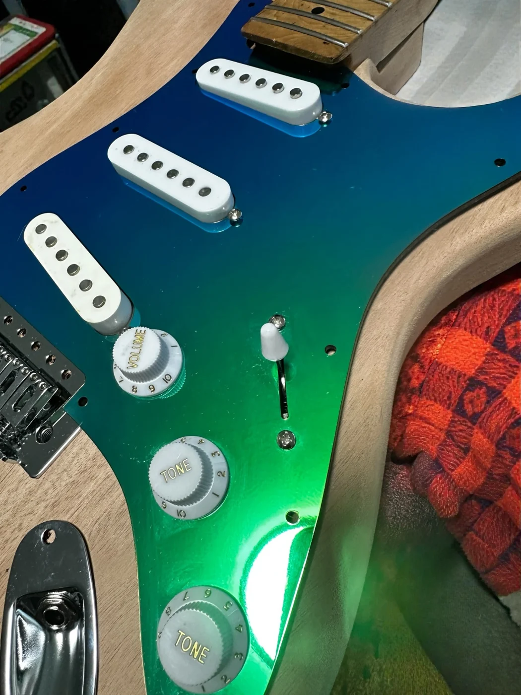 Blue and green mirror pickguard installed on a Strat-style guitar